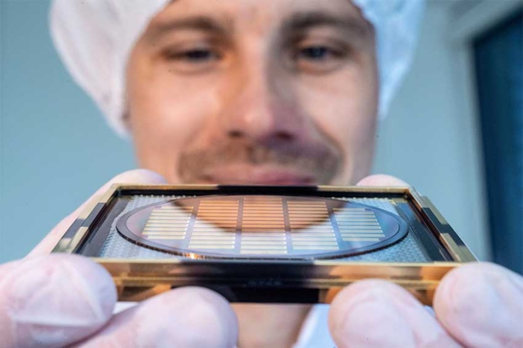 A Q.ant employee holds up a wafer from which photonic chips are cut. (Source:...