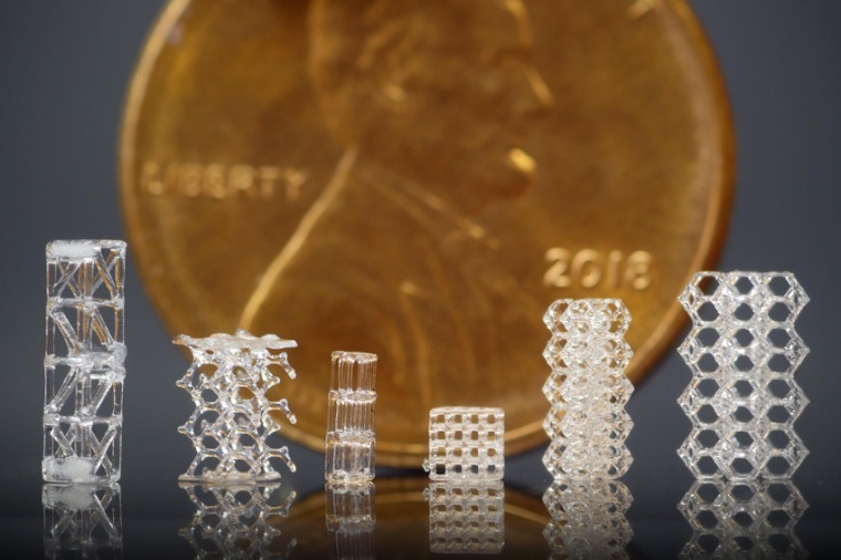 3D-printed glass lattices, displayed in front of a U.S. penny for scale....