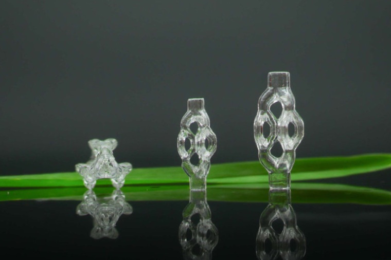 3D-printed, trifurcated microtubule models, displayed beside a blade of grass....