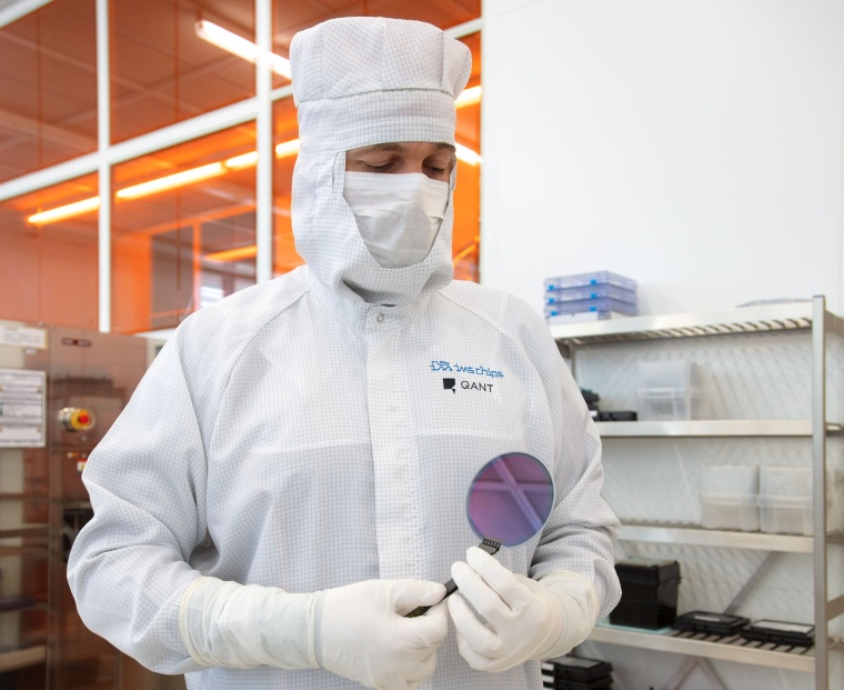 An employee inspects a quantum wafer under clean room conditions. (Source: Qant)