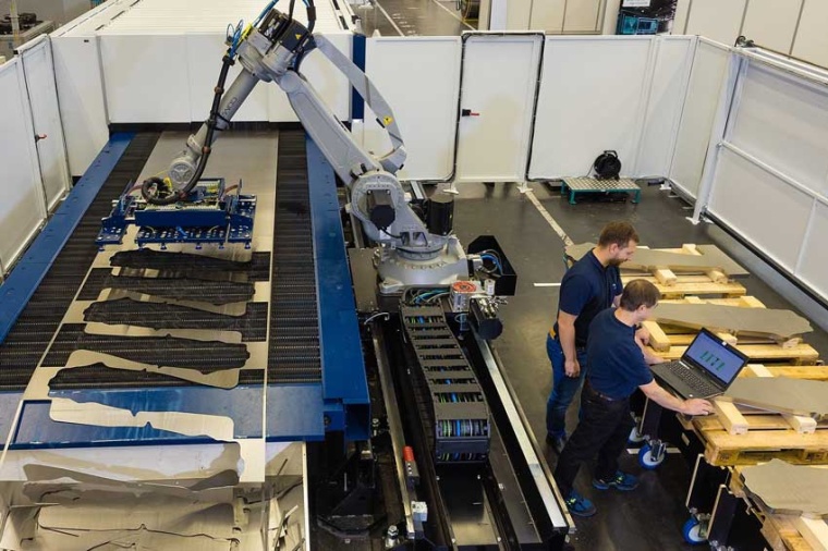Two workers prepare the laser system for processing sheet-metal blanks for...