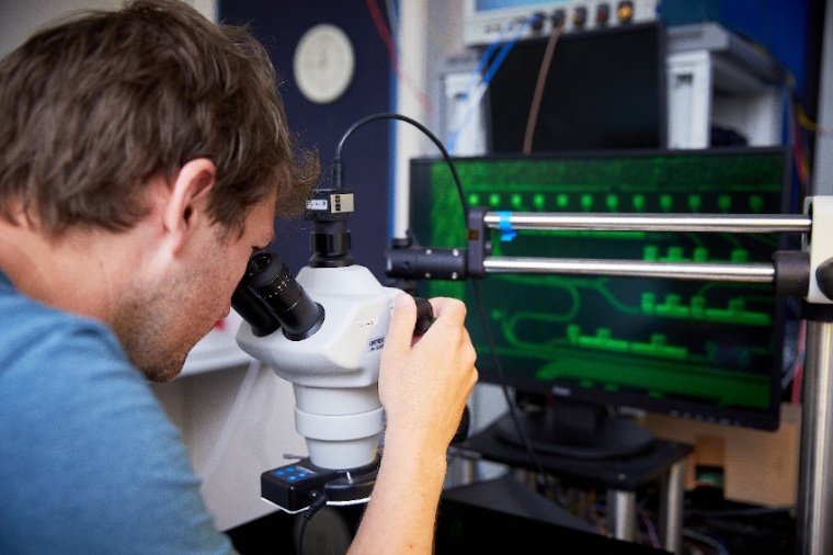 A Toshiba scientist examines a quantum key distribution chip under the...