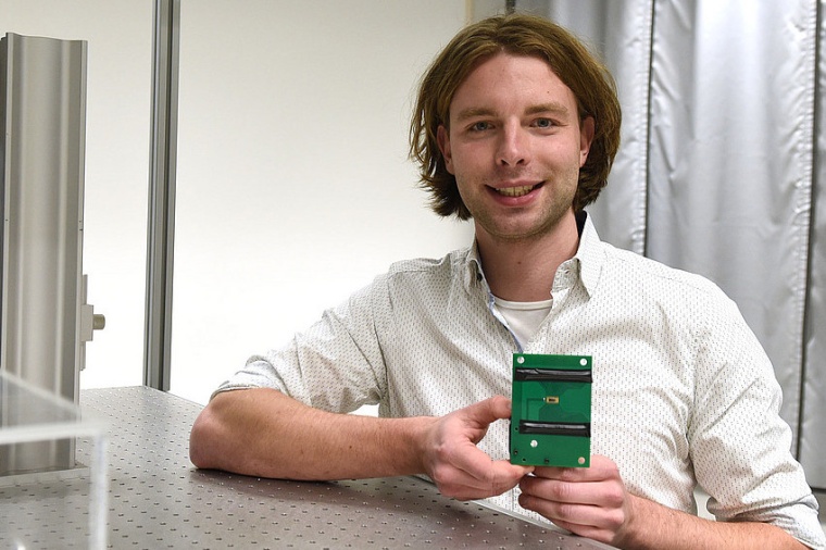 Researcher Johannes Bütow with his new photonic chip that can generate and...