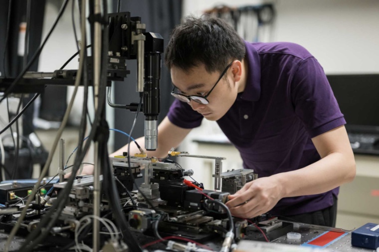 Researcher Zhengdong Gao adjusts a new “all in one” microcomb laser device....